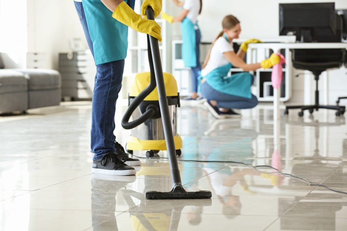 Janitor hoovering floor in office Genetorial cleaning