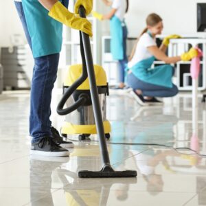 Janitor hoovering floor in office Genetorial cleaning