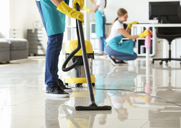 Janitor hoovering floor in office Genetorial cleaning